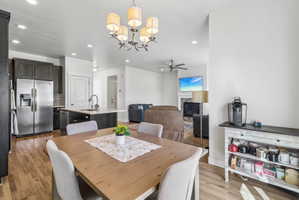 Dining room with light wood-style floors, a glass covered fireplace, suspended lighting, and ceiling fan