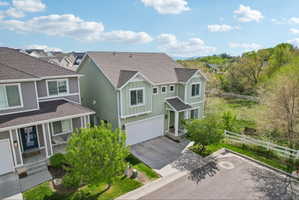View of front facade featuring board and batten siding, a shingled roof, a garage, and driveway