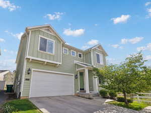 View of front of house with board and batten siding, an attached garage, and driveway