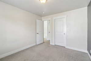 Unfurnished bedroom with baseboards and light colored carpet