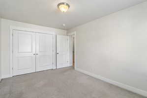 Unfurnished bedroom featuring light carpet and a closet