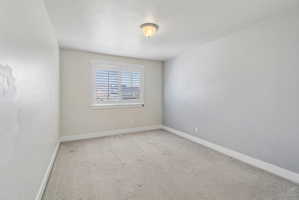 Spare room with baseboards and light colored carpet