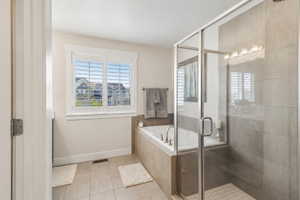 Full bath with a shower stall, light tile patterned floors, and a bath