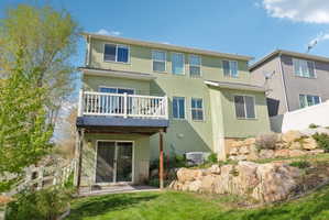 Rear view of house featuring stucco siding and a balcony