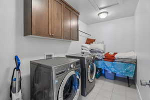 Laundry area with cabinet space, light tile patterned flooring, and washer and dryer