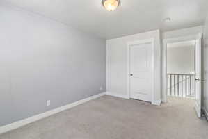 Empty room featuring light colored carpet and a smoke detector