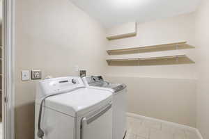Laundry room with washer and dryer and light tile patterned floors