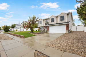 Split foyer home with a gate, driveway, an attached garage, and brick siding