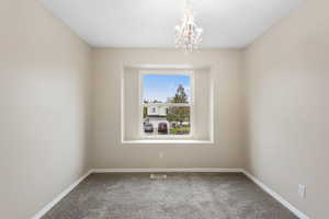 Empty room featuring light colored carpet and hanging lights