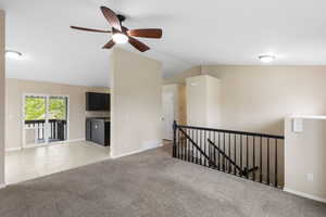 Unfurnished room with light colored carpet, vaulted ceiling, and ceiling fan