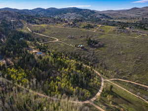 Aerial overview of property's location with a mountain backdrop and property boundaries highlighted