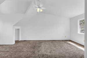 Master bedroom featuring a ceiling fan, vaulted ceiling, and carpet floors