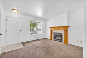 Unfurnished living room with light carpet, a fireplace, and light tile patterned floors