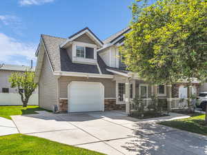 View of front of home featuring a shingled roof, driveway, stone siding, and a garage