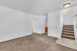 Unfurnished living room with light colored carpet and light tile patterned floors