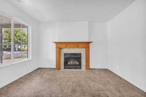 Unfurnished living room with carpet flooring and a tiled fireplace
