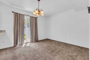 Unfurnished room with suspended lighting and dark carpet
