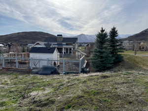 Back of property featuring a mountain view, a chimney, and a yard