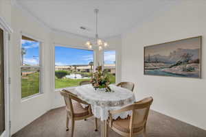 Carpeted dining area featuring crown molding, a chandelier, and a water view