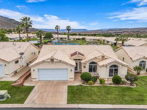 Mediterranean / spanish-style house with a residential view, stucco siding, a garage, driveway, and a front lawn