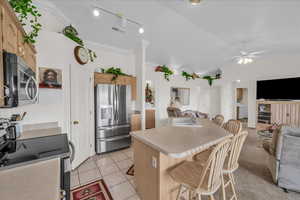 Kitchen featuring open floor plan, a breakfast bar area, stainless steel appliances, an island with sink, and crown molding