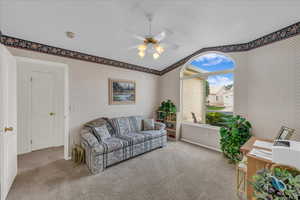 Living area with wallpapered walls, ceiling fan, carpet flooring, and vaulted ceiling