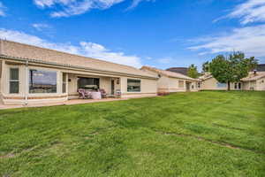 Back of house with a yard, stucco siding, a patio area, and a tile roof