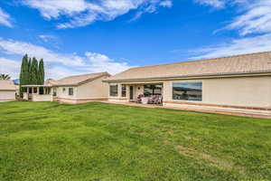 Back of property featuring stucco siding, a tiled roof, and a lawn