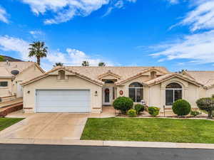 Mediterranean / spanish home featuring stucco siding, an attached garage, concrete driveway, a front lawn, and a tile roof
