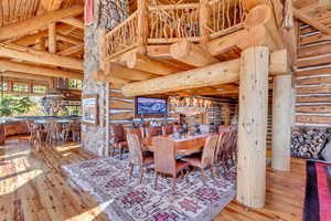 Dining space featuring log walls, wood-type flooring, and a high wooden beamed ceiling