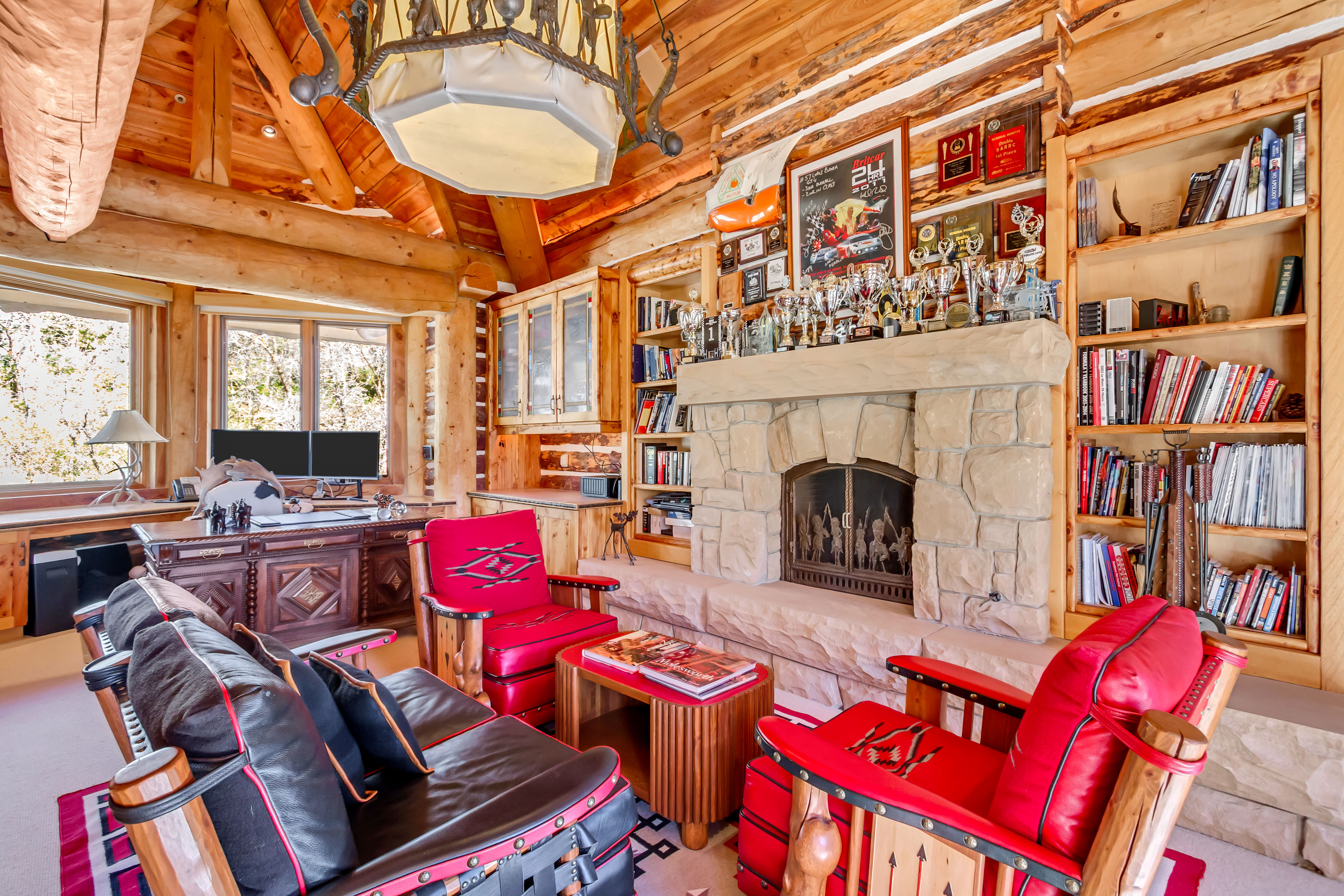 Living area with a stone fireplace, rustic walls, and carpet flooring