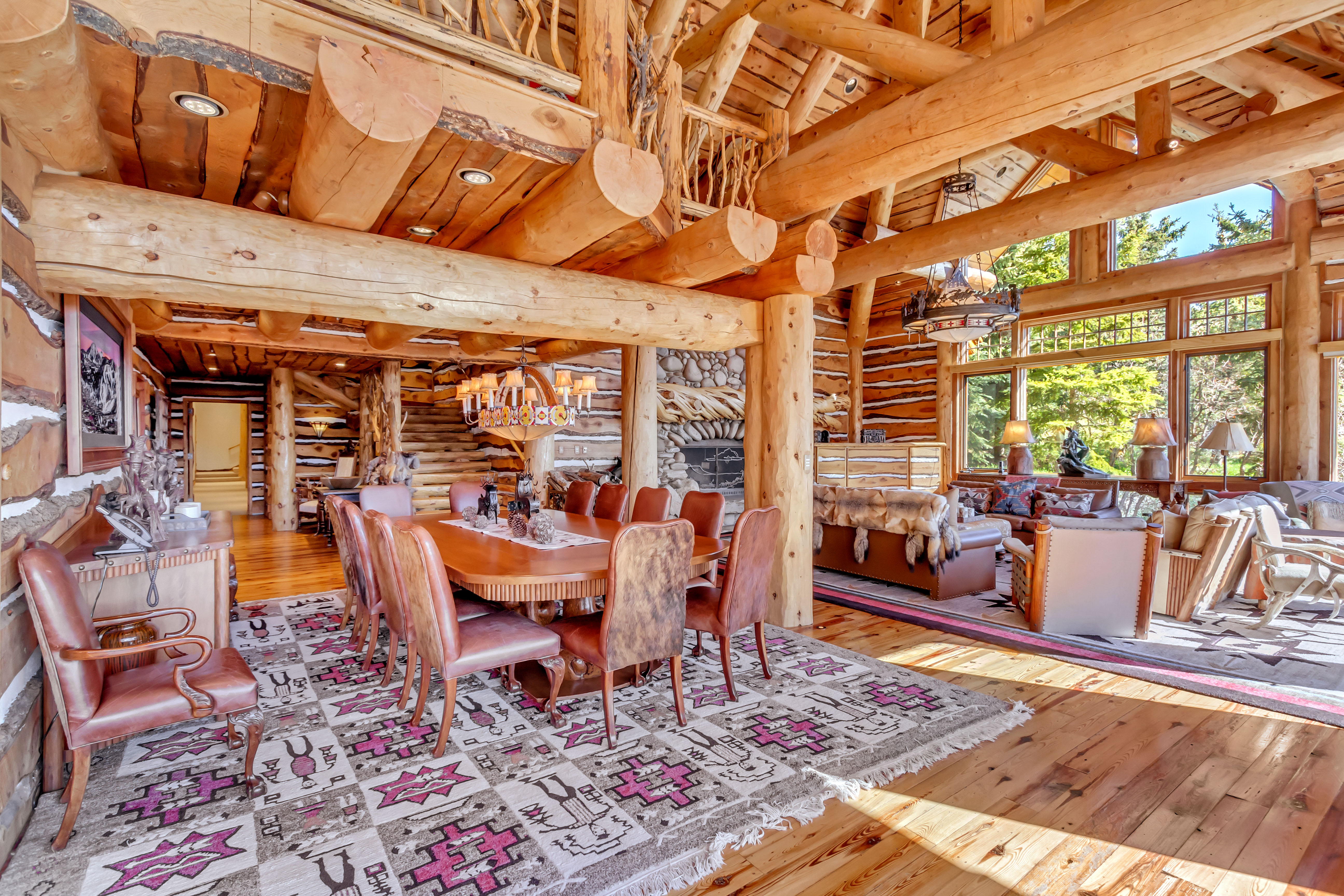Dining space with log walls, light wood finished floors, suspended lighting, and a high wood beamed ceiling