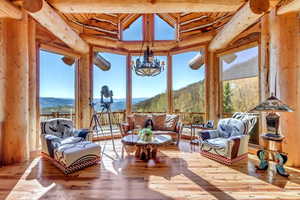 Sunroom with wood-type flooring, a mountain view, rustic walls, and suspended lighting