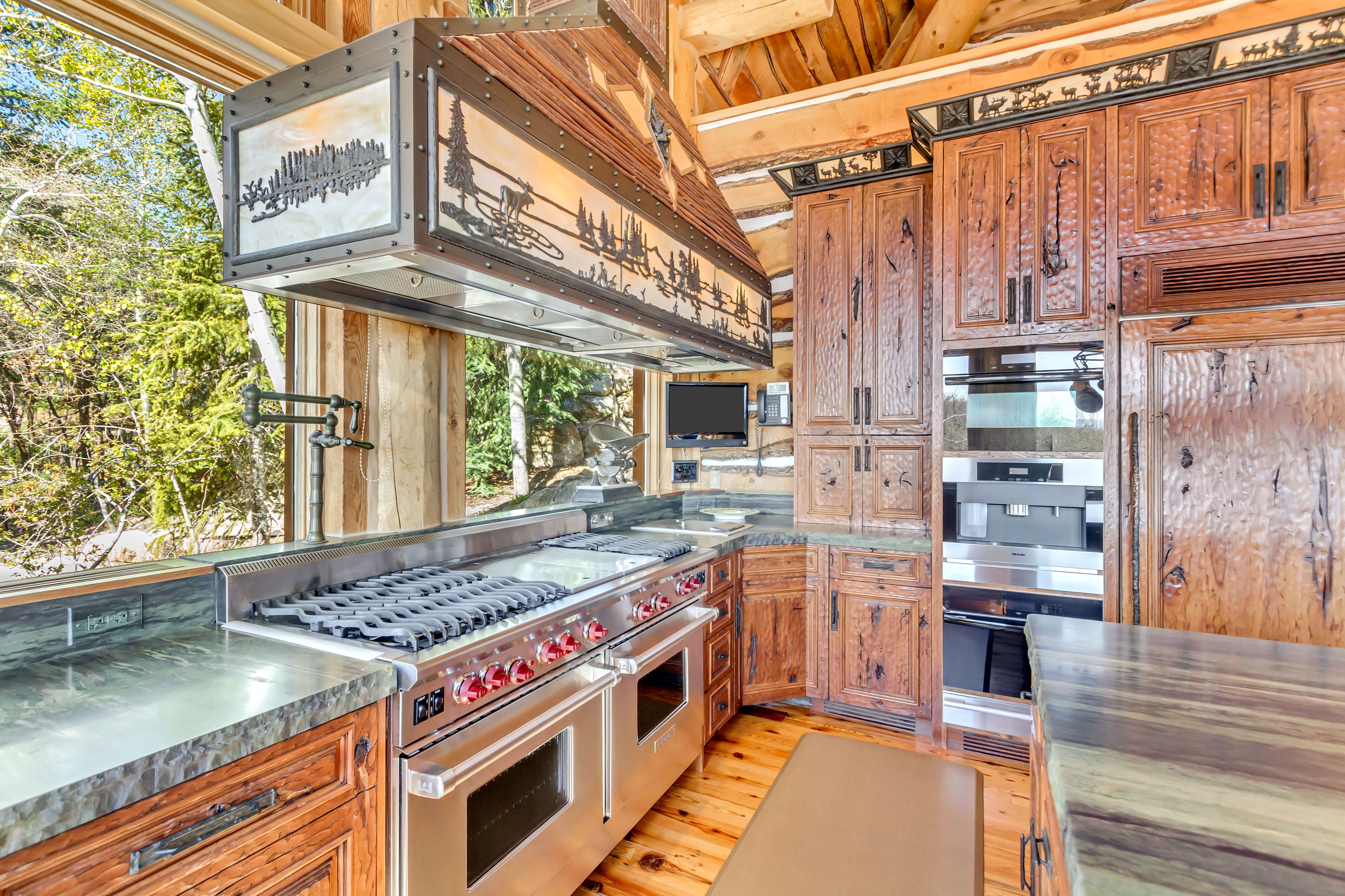 Kitchen with wood finish cabinets, stainless steel appliances, ventilation hood, wood counters, and light wood-style flooring