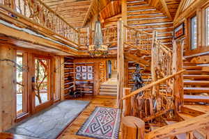 Staircase featuring hardwood / wood-style flooring, hanging lights, a high wooden ceiling, and rustic walls