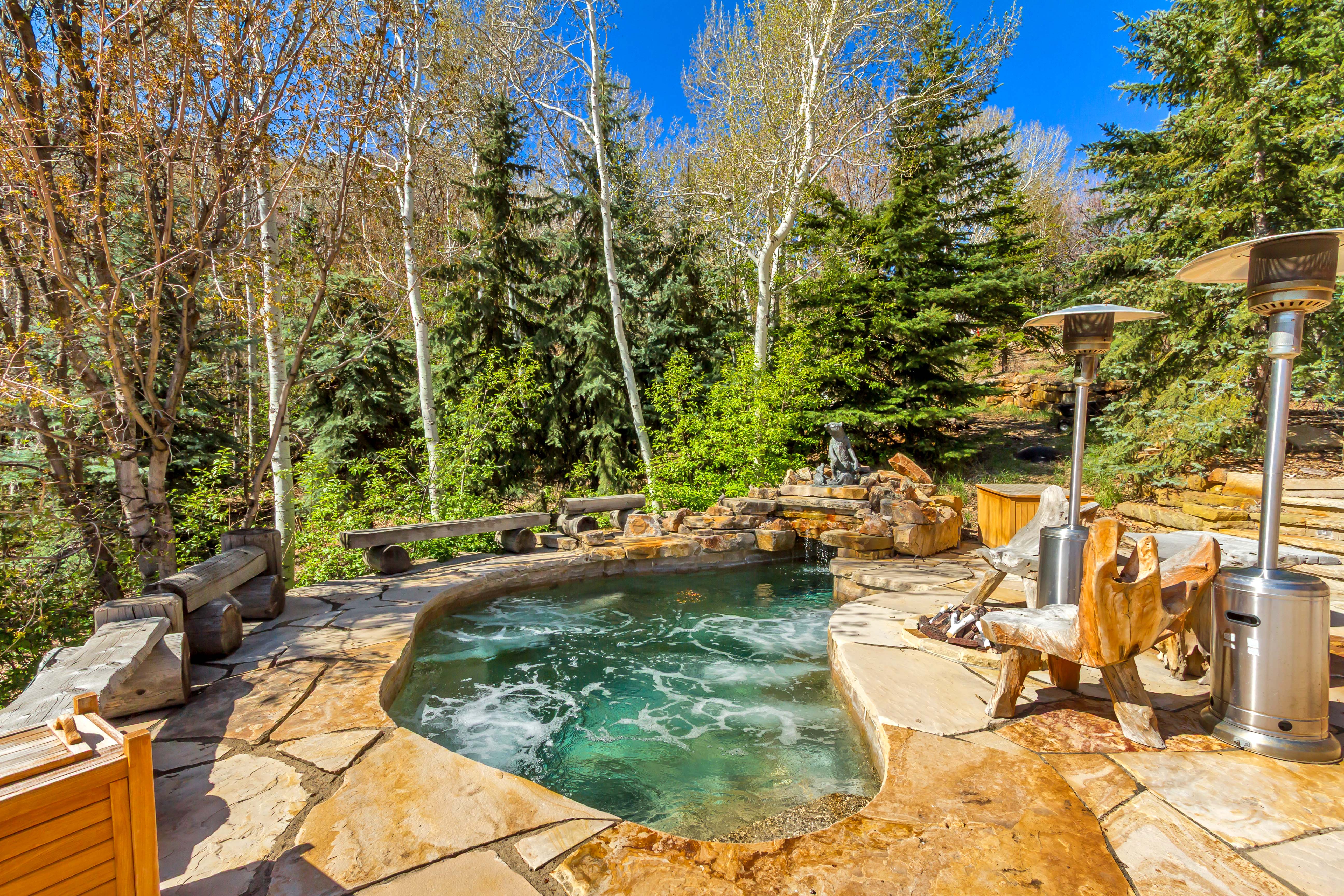 View of swimming pool featuring a jacuzzi, patio surround, and view of wooded area