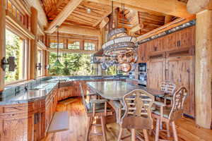 Kitchen featuring wood finish cabinetry, light wood finished floors, dark countertops, and a wood ceiling with exposed beams