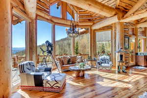 Sunroom with suspended lighting, healthy amount of natural light, and vaulted ceiling with beams