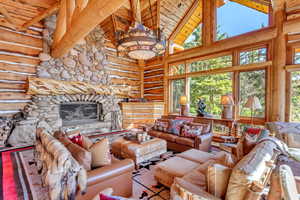 Living area featuring rustic walls, a high wooden ceiling, and a fireplace