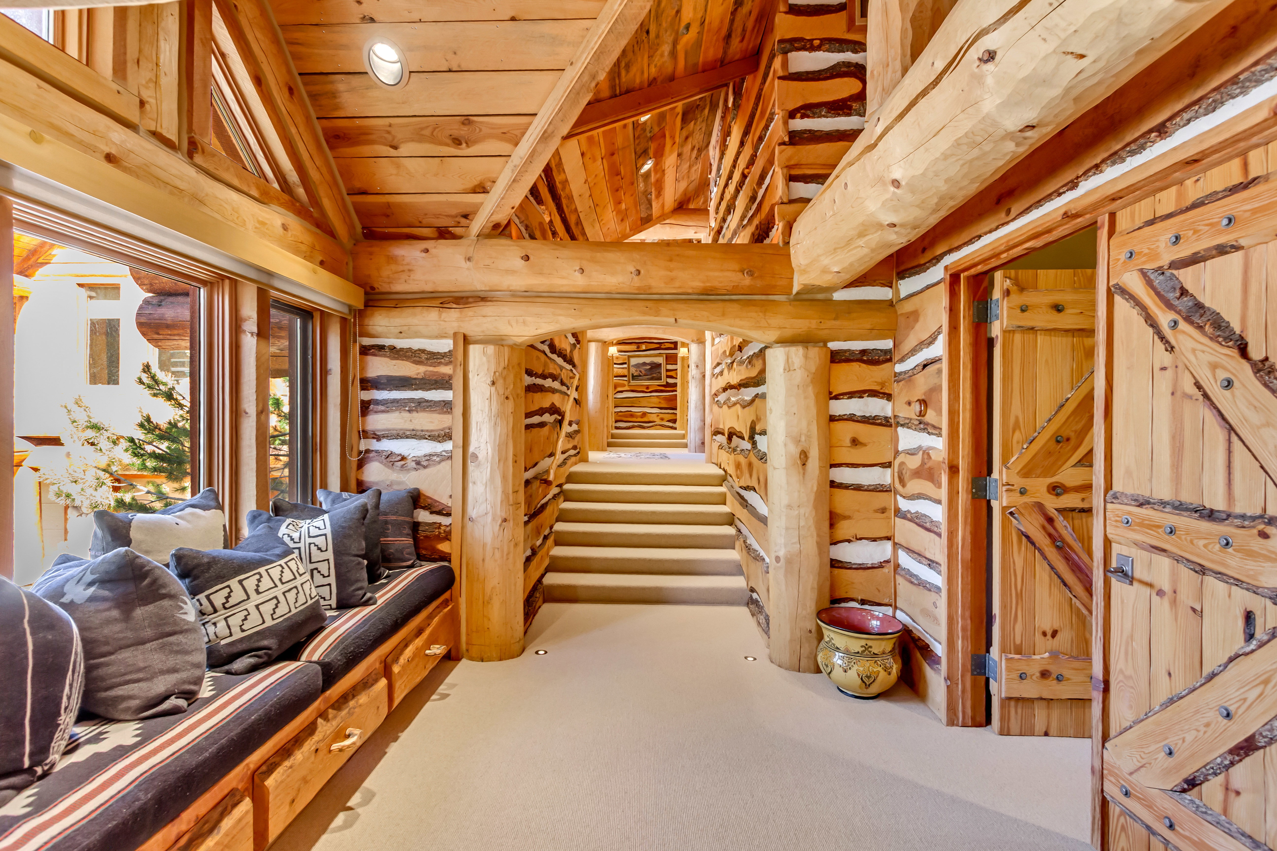 Living area featuring a vaulted wooden ceiling, rustic walls, and light colored carpet
