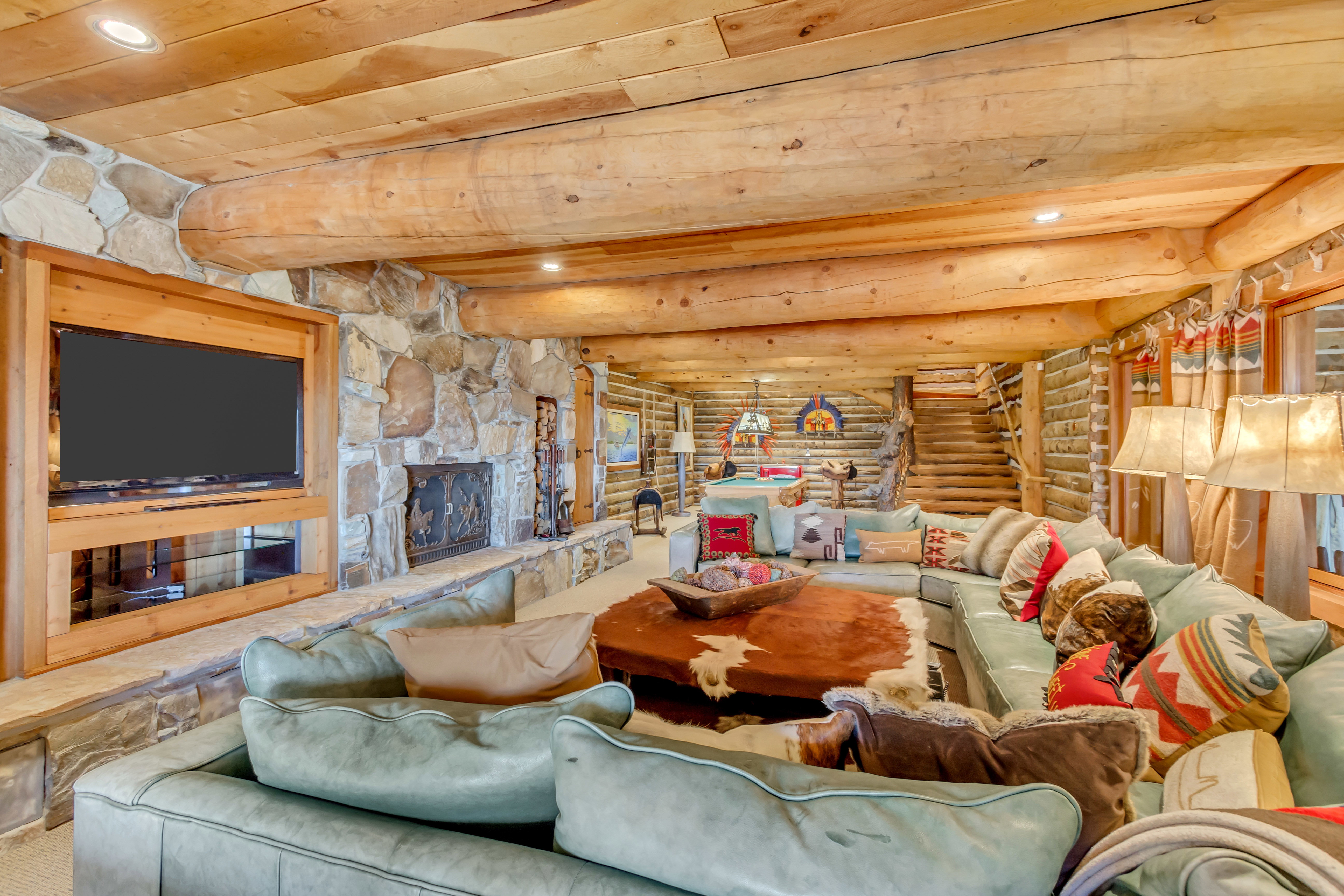 Carpeted living area with log walls, a fireplace, recessed lighting, and a wooden ceiling with exposed beams