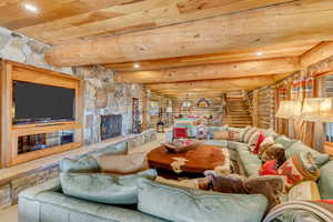 Carpeted living area with log walls, a fireplace, recessed lighting, and a wooden ceiling with exposed beams