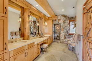 Full bathroom featuring a stall shower, double vanity, beamed ceiling, stone flooring, and recessed lighting
