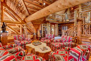 Living room with rustic walls and a high wood beamed ceiling