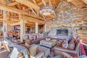 Living room featuring rustic walls, a fireplace, and a high wood beamed ceiling
