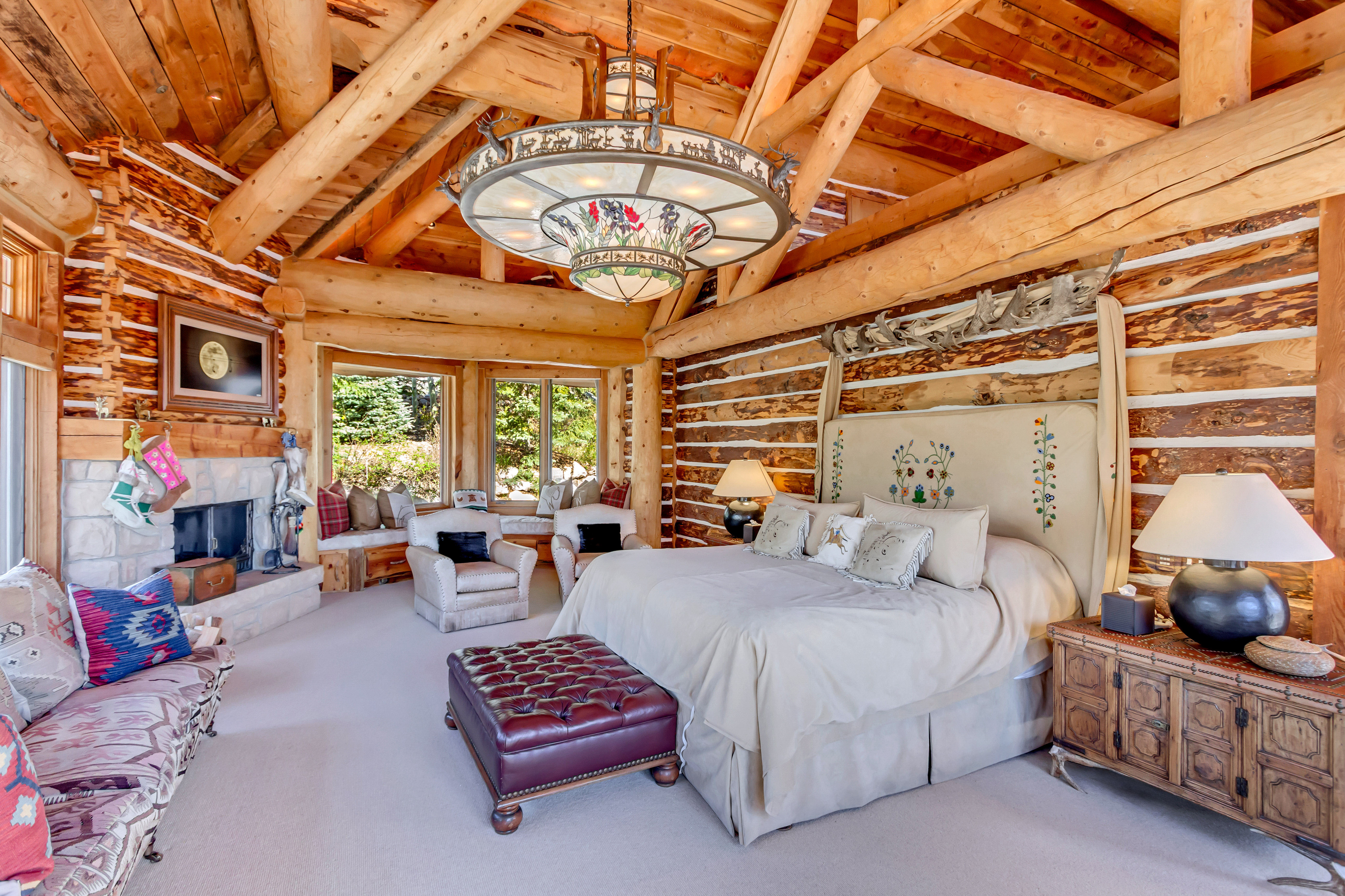 Bedroom featuring rustic walls, carpet, a stone fireplace, and a high wooden beamed ceiling