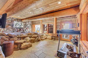 Misc room featuring stone flooring, recessed lighting, log walls, and wooden ceiling