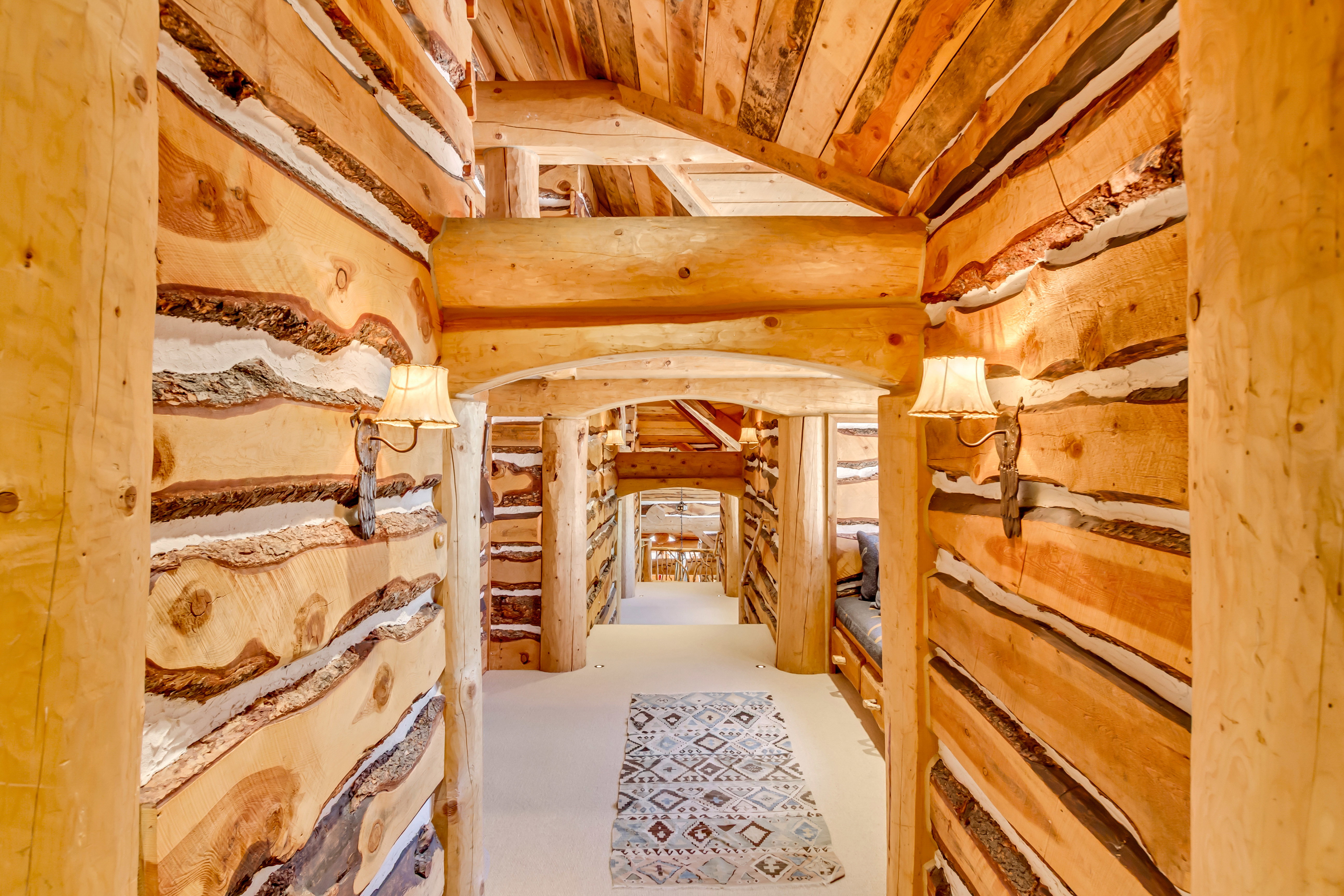 Hall featuring arched walkways, log walls, a vaulted wood ceiling, and decorative columns