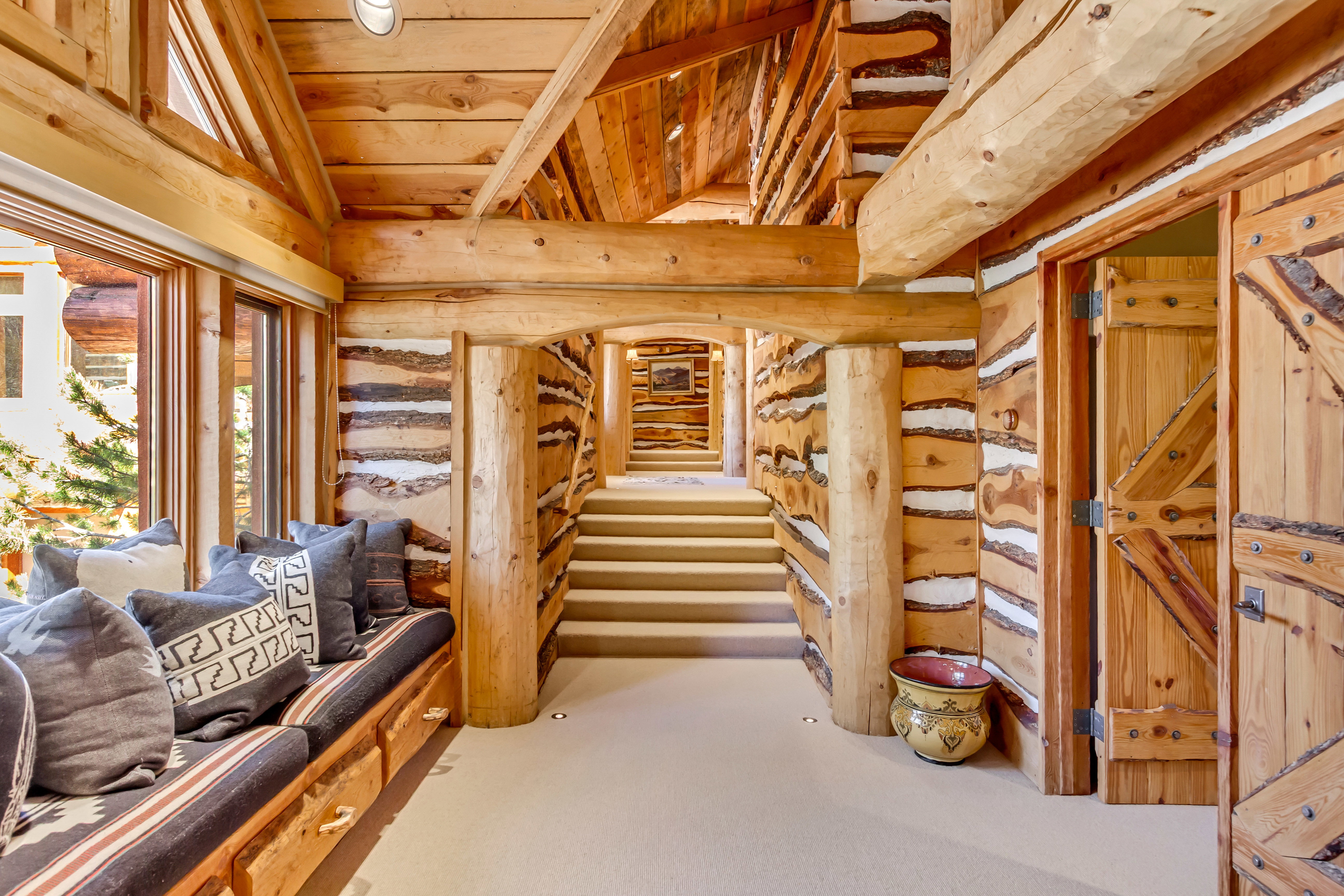 Sitting room featuring a vaulted wooden ceiling, log walls, and light colored carpet