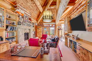 Living room with a high wood beamed ceiling, rustic walls, and a stone fireplace